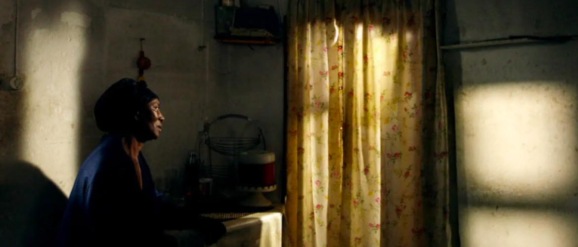 mujer afro sentada mirando hacia la ventana 