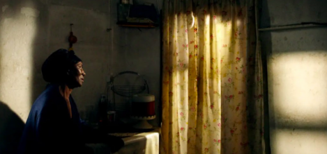 mujer afro sentada mirando hacia la ventana 