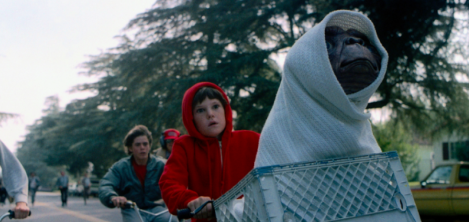 Dos jovenes en bicicleta con un extraterrestre en la canasta 