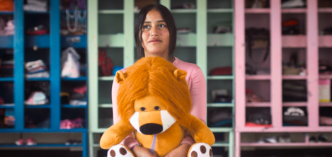 Niña sentada con un león de peluche en las manos