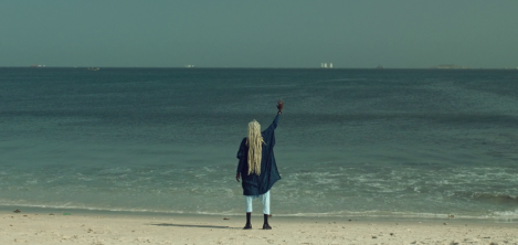 Mujer afro frente al mar alzando la mano